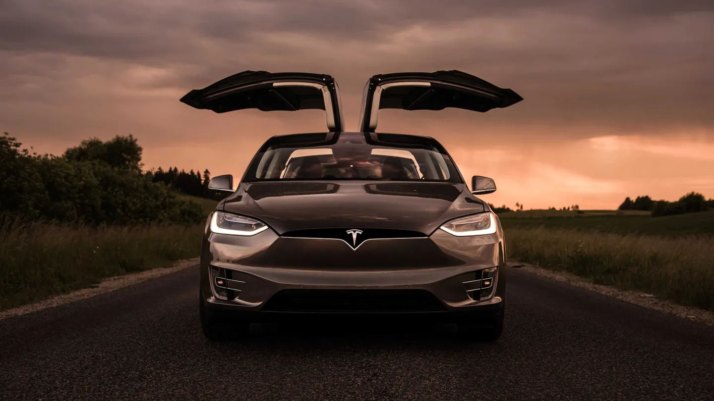 A Tesla with its falcon-wing doors open at sunset