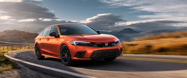 An orange Honda Civic Si driving on a road