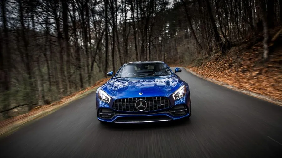 A blue Mercedes sports car on a wooded road