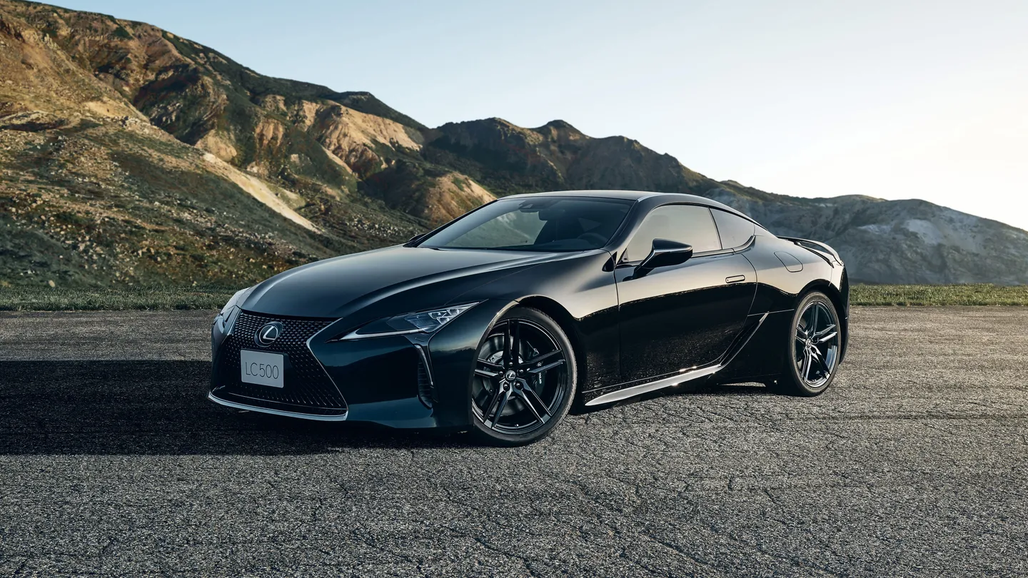 A black Lexus LC coupe beside a rocky coast