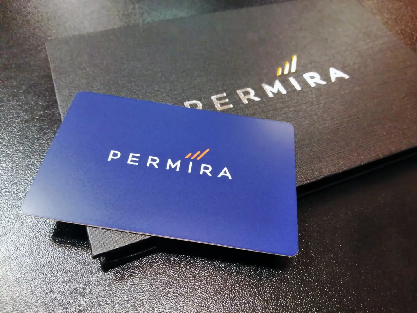 A blue Permira metal card with its presentation box