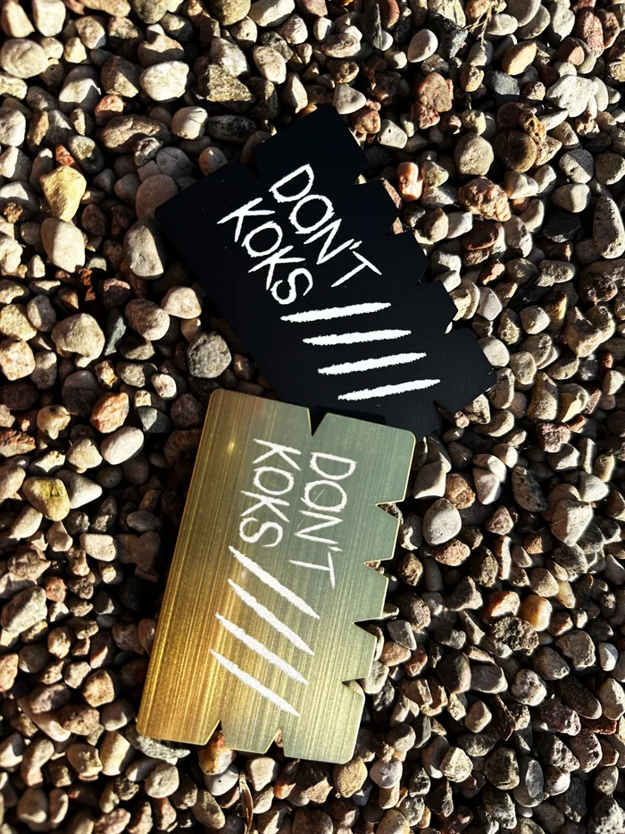 Black and gold Mont Frost metal cards on pebbles