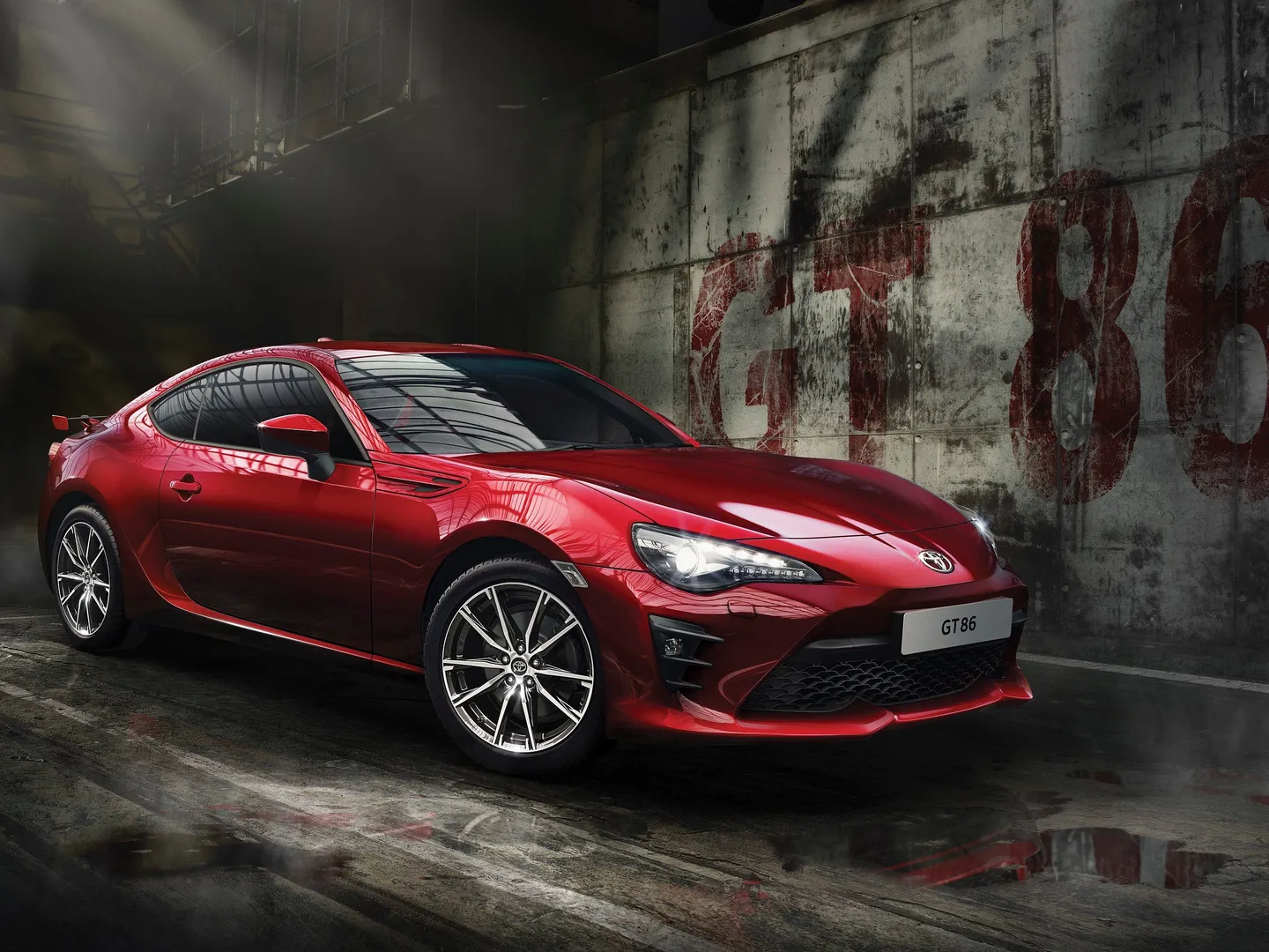A red Toyota sports car in an industrial setting