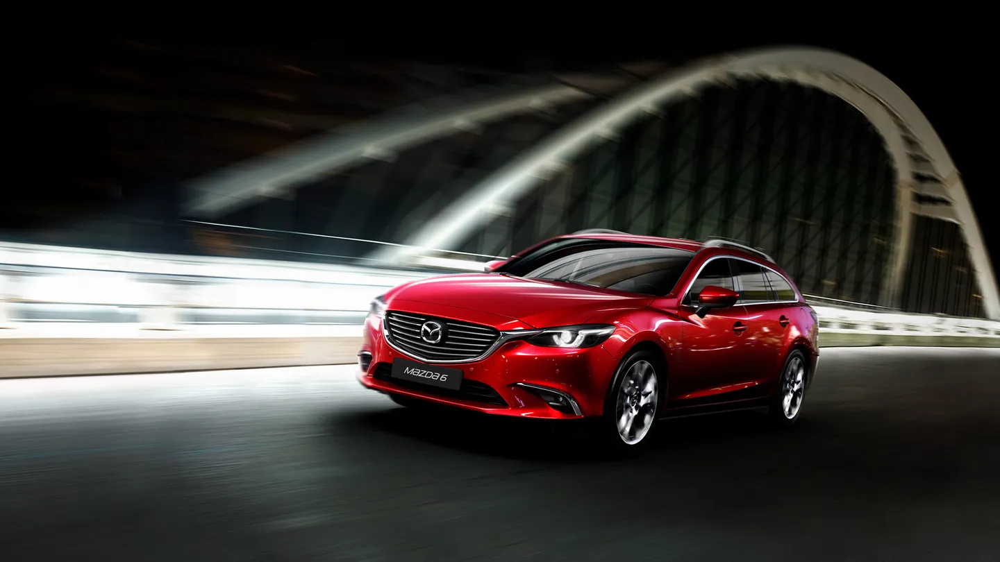 A red Mazda saloon on an illuminated road